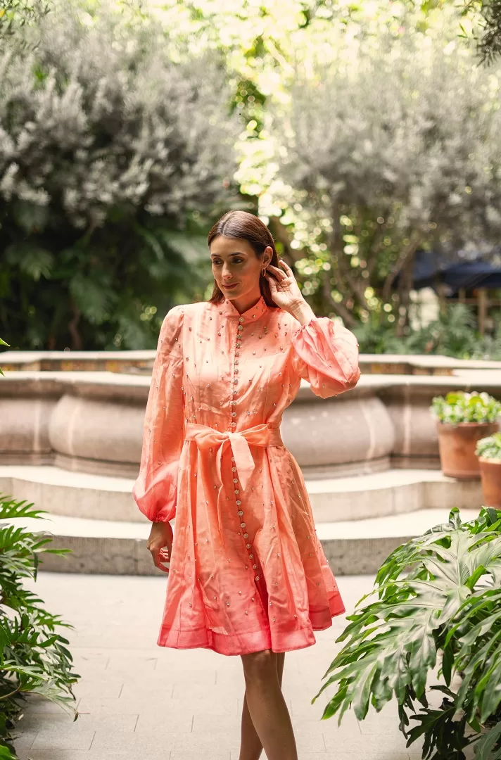 Vestido corto con efecto ombré, manga larga abullonada, botones joya al frente y aplicaciones brillantes. Disponible en rosa/naranja y verde/azul. El look perfecto para brillar este verano.