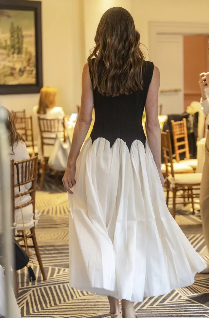 Vestido bicolor blanco con negro de corte maxi-midi, con corset liso sin mangas y falda amplia con ondas estructuradas. Una silueta escultural y elegante que fusiona lo clásico con lo moderno.