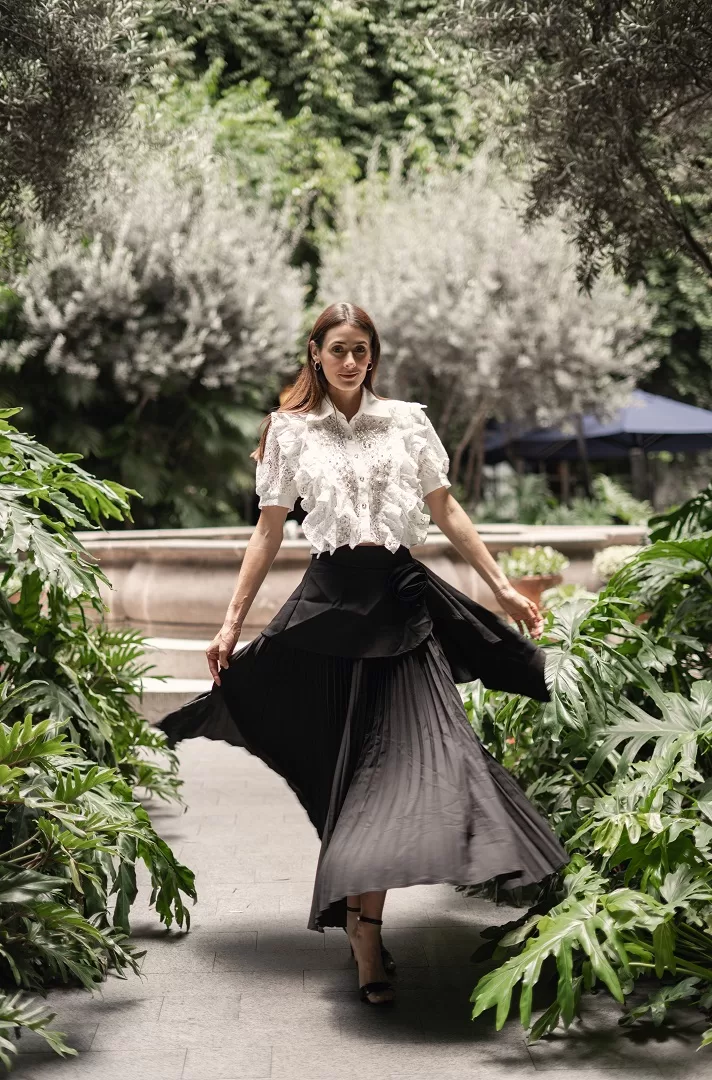 Maxi falda negra plisada con detalle de flor drapeada. Una pieza elegante y atemporal que combina estructura, feminidad y movimiento.