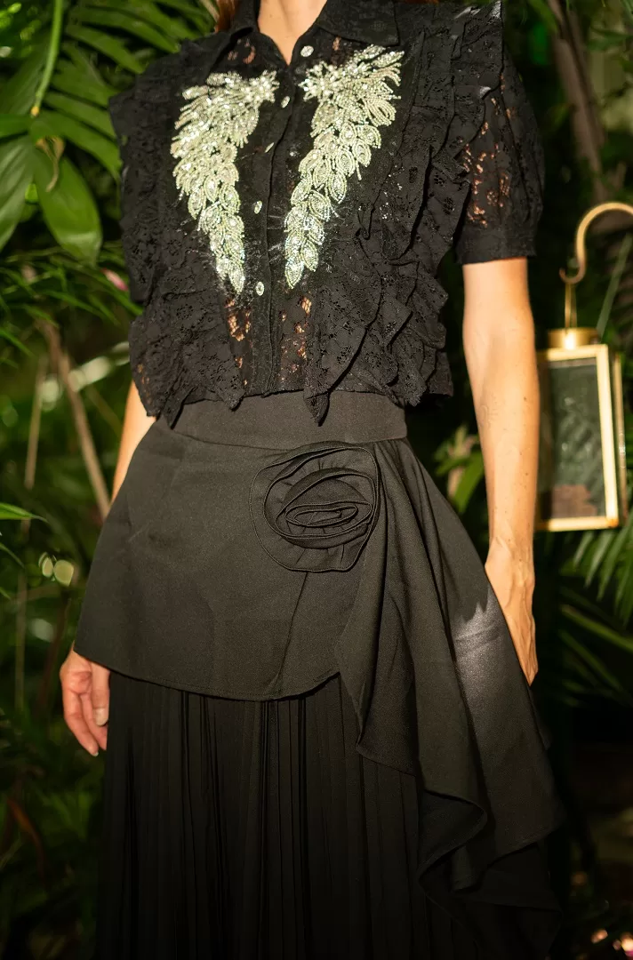 Maxi falda negra plisada con detalle de flor drapeada. Una pieza elegante y atemporal que combina estructura, feminidad y movimiento.