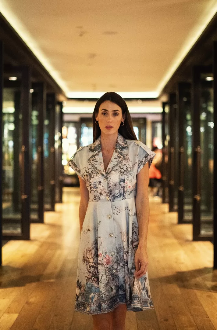 Vestido camisero con print artístico estilo toile de Jouy en tonos suaves, cuello estructurado, hombreras con botón dorado y pedrería en solapas. Elegancia atemporal con espíritu moderno.