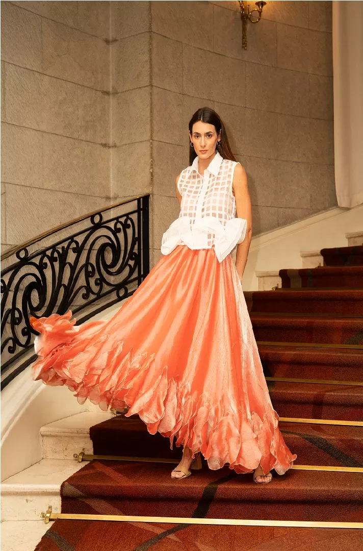 Falda midi rosa con olanes asimétricos y caída fluida en textil satinado. Una pieza statement con movimiento espectacular y elegancia única.