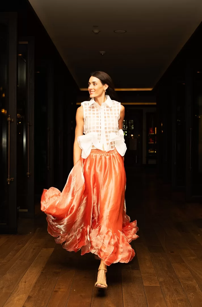 Falda midi rosa con olanes asimétricos y caída fluida en textil satinado. Una pieza statement con movimiento espectacular y elegancia única.